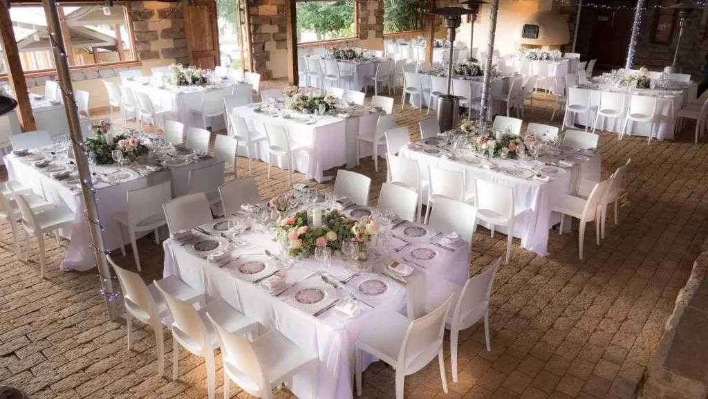 A stunning wedding reception with square tables setup on a cobblestone floor.