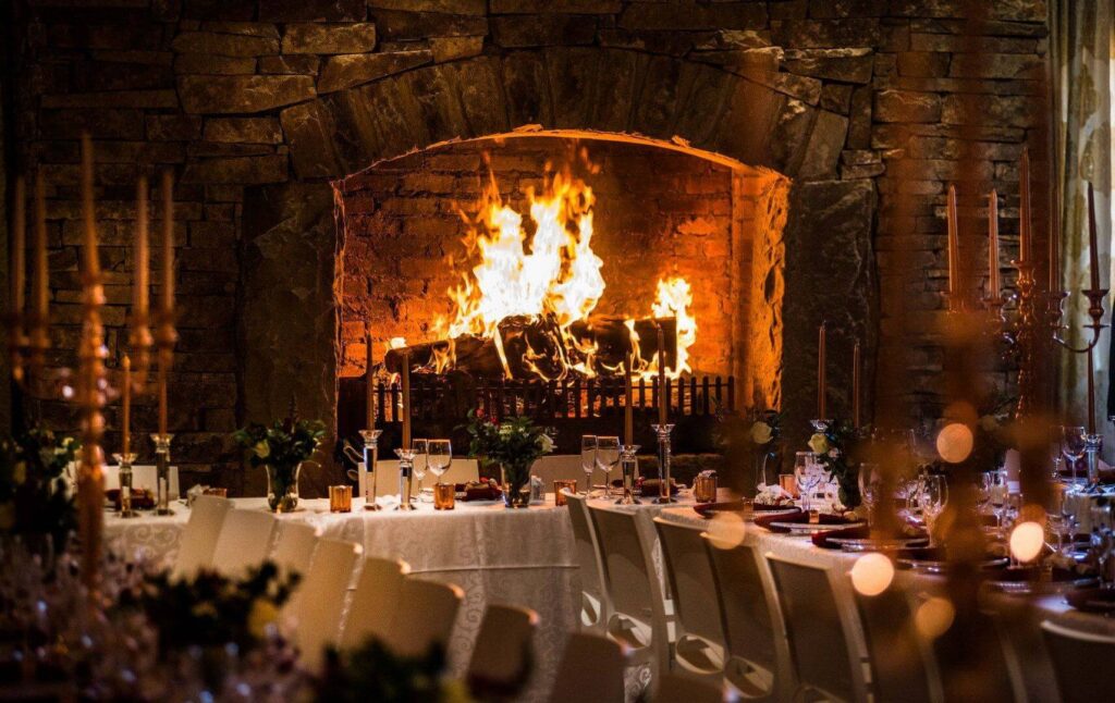A large wedding reception fireplace behind chairs and tables.
