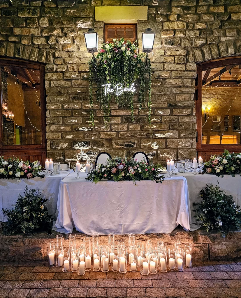 A table set up with candles in front of a stone wall.